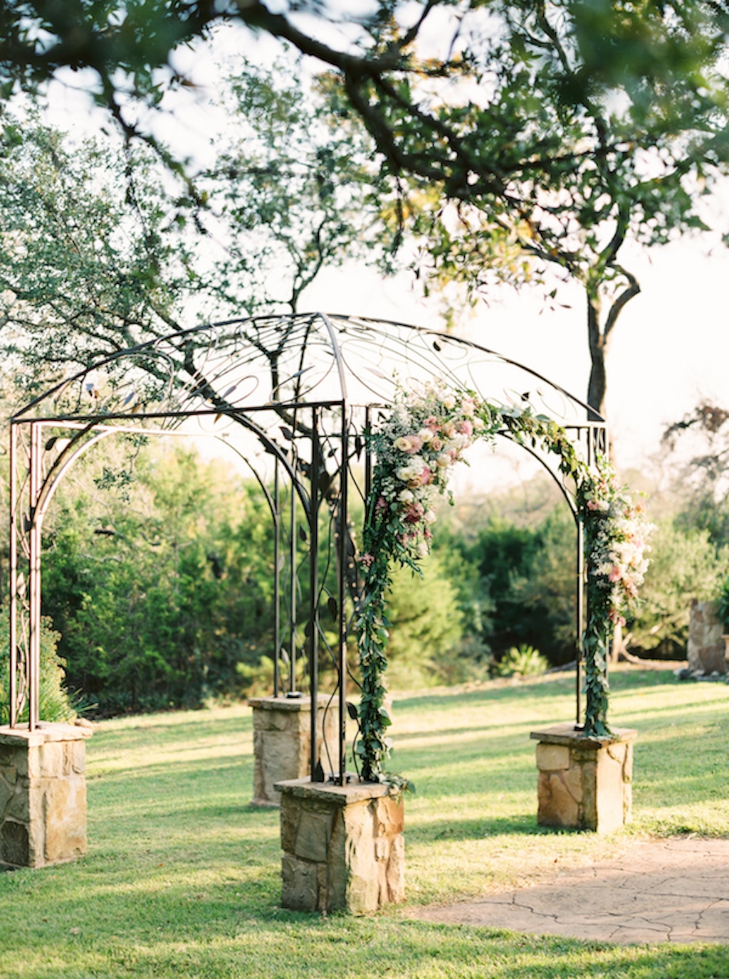 Sun shines on a ceremony arbor at Kindred Oaks, a wedding venue in Georgetown, Texas.