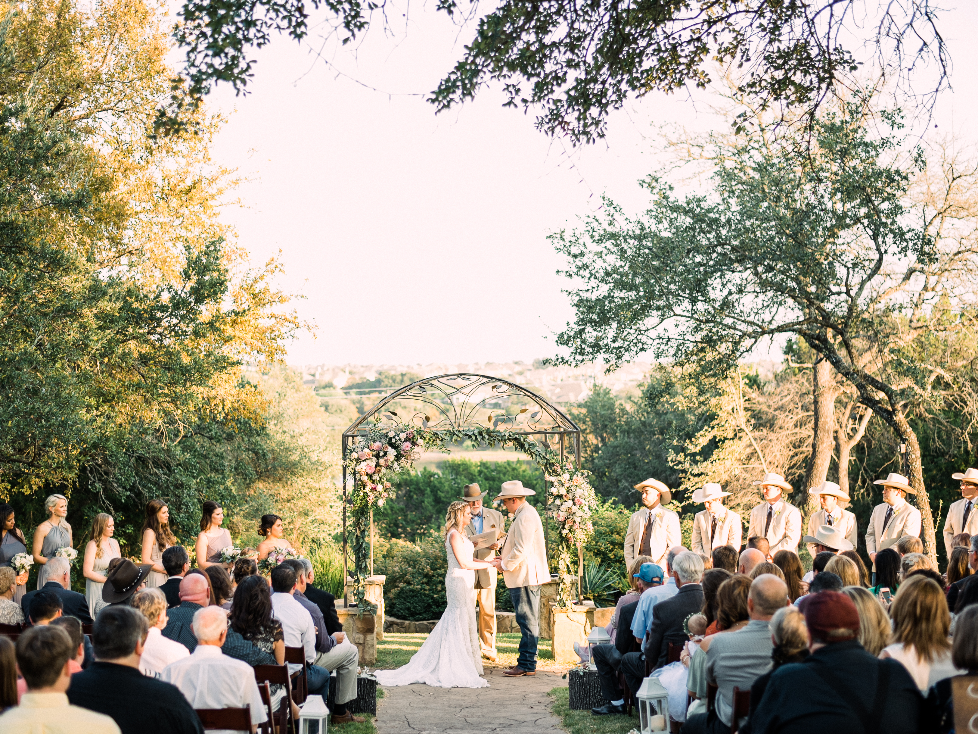 A bride and groom face each other while they say their vows during their sunny, outdoor wedding ceremony in Georgetown, Texas.