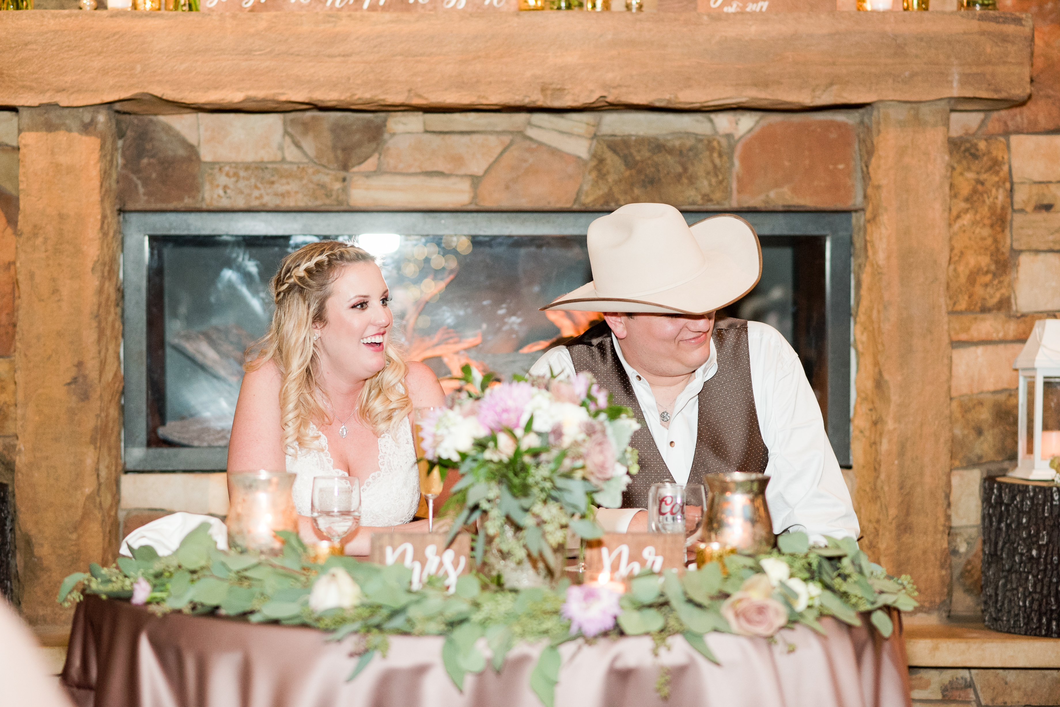 A bride and groom sit at their sweetheart table during their wedding reception at Kindred Oaks in Georgetown, Texas.