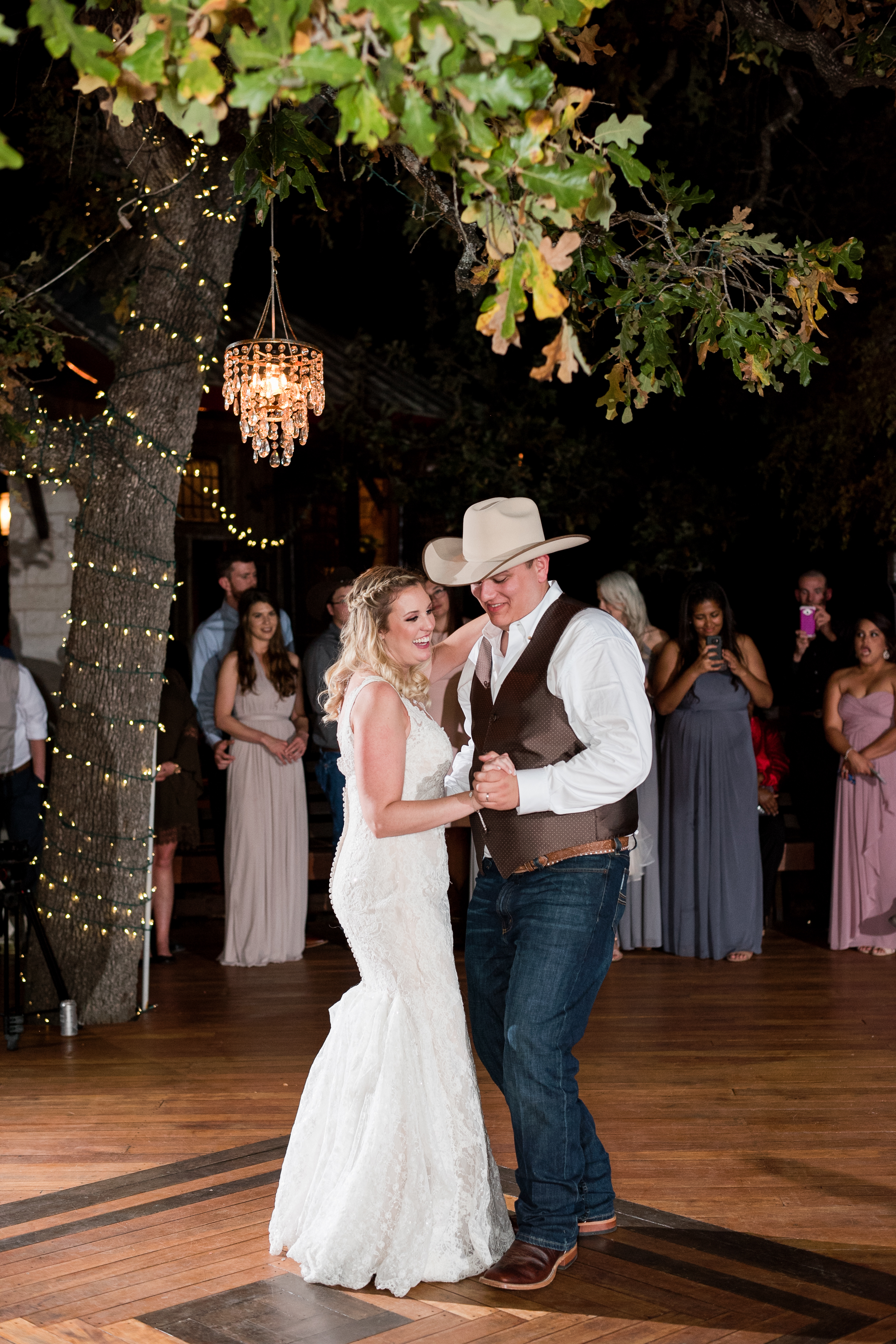 A bride and groom hold hands and dance on the wooden dance floor in Georgetown, Texas at their outdoor wedding.