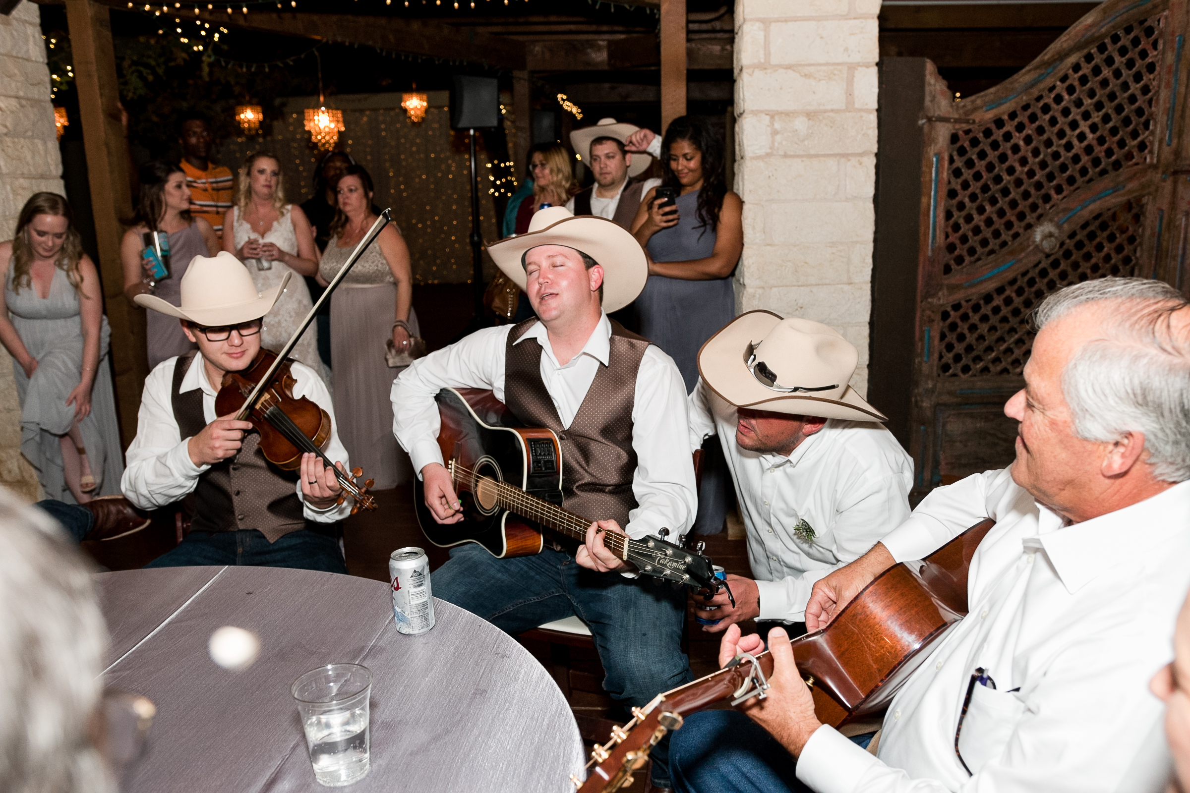 A group of men play live music on guitars at a wedding reception in Georgetown, Texas